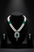 Pearl and teal AD pendant necklace set with earrings on dark velvet studio display