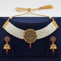 Multi-strand seed pearl choker with ruby and emerald circular disc centrepiece and jhumka set on navy velvet display