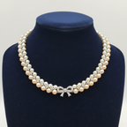Double-strand champagne pearl and AD X-link necklace with bow clasp on navy velvet bust display