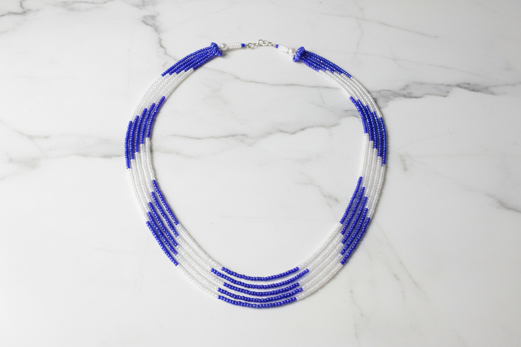 Flat lay of blue and white seed bead necklace on white marble
