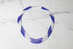 Flat lay of blue and white seed bead necklace on white marble