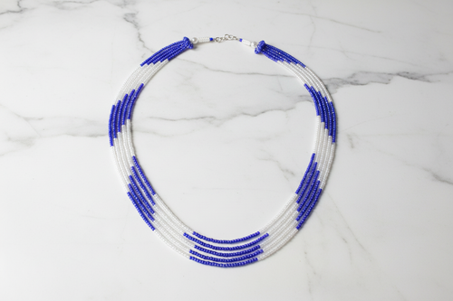 Flat lay of blue and white seed bead necklace on white marble