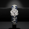Navy blue sapphire baguette AD bangle with white floral AD sculpture on dark velvet studio display