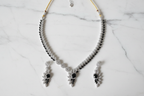 Black onyx leaf AD necklace set flat lay on white marble