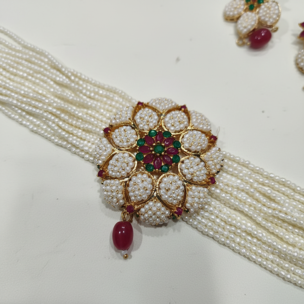 Close-up detail of multi-strand seed pearl choker with AD floral medallion and ruby emerald centre