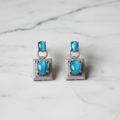 Turquoise cat-eye square frame drop earrings editorial promotional image on marble