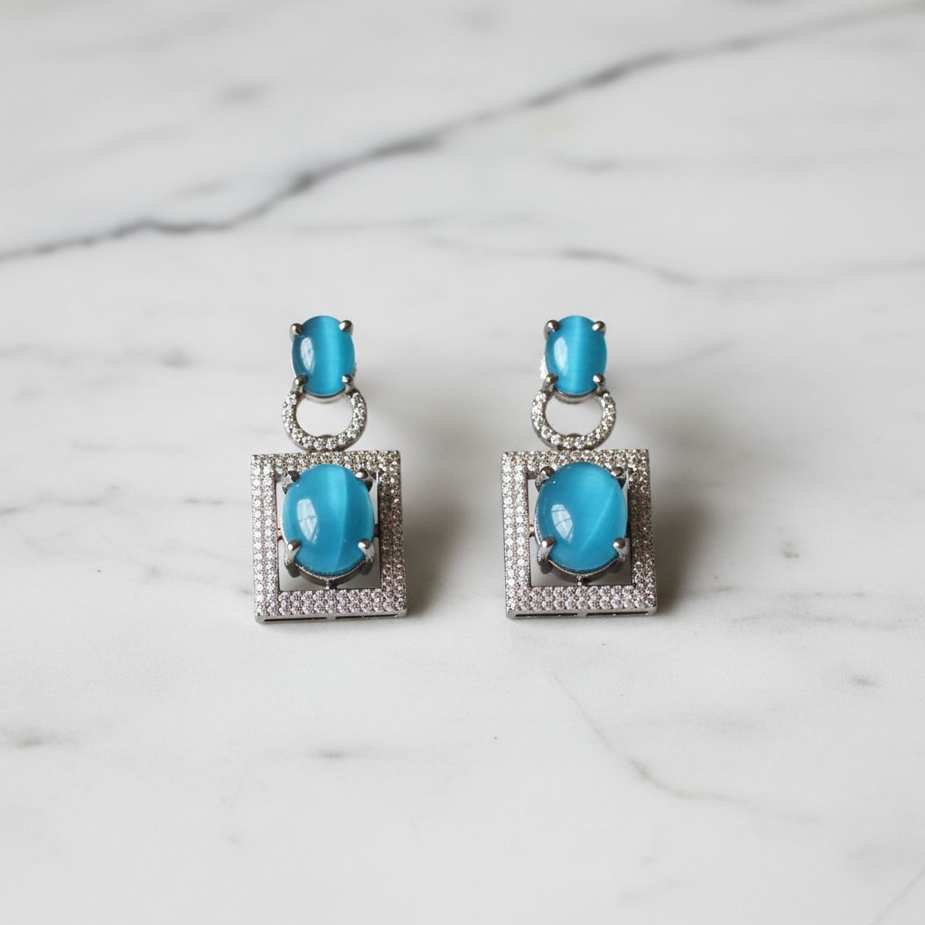 Turquoise cat-eye square frame drop earrings editorial promotional image on marble