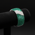 Emerald baguette and white AD pavé wave bangle bracelet on dark velvet studio display