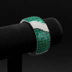 Emerald baguette and white AD pavé wave bangle bracelet on dark velvet studio display