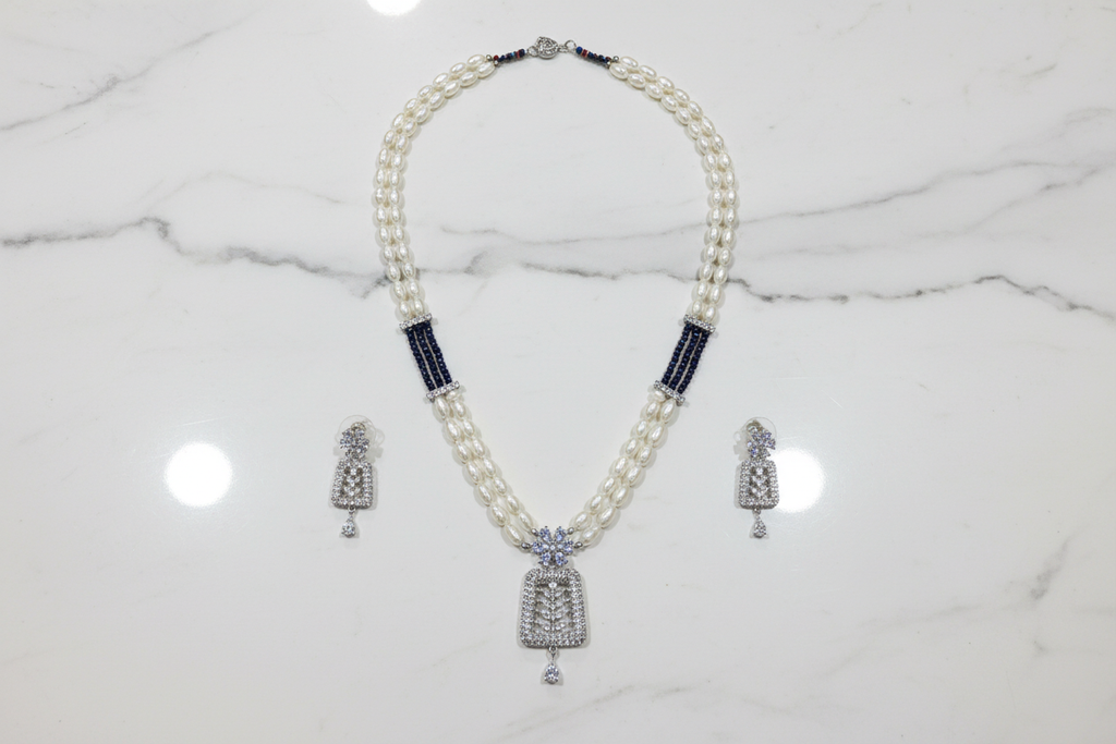 Flat lay of pearl and AD pendant necklace set with earrings on white marble