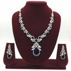 White AD and sapphire blue floral leaf pendant necklace set on burgundy velvet display