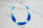 Flat lay of blue and white ombre seed bead necklace on white marble