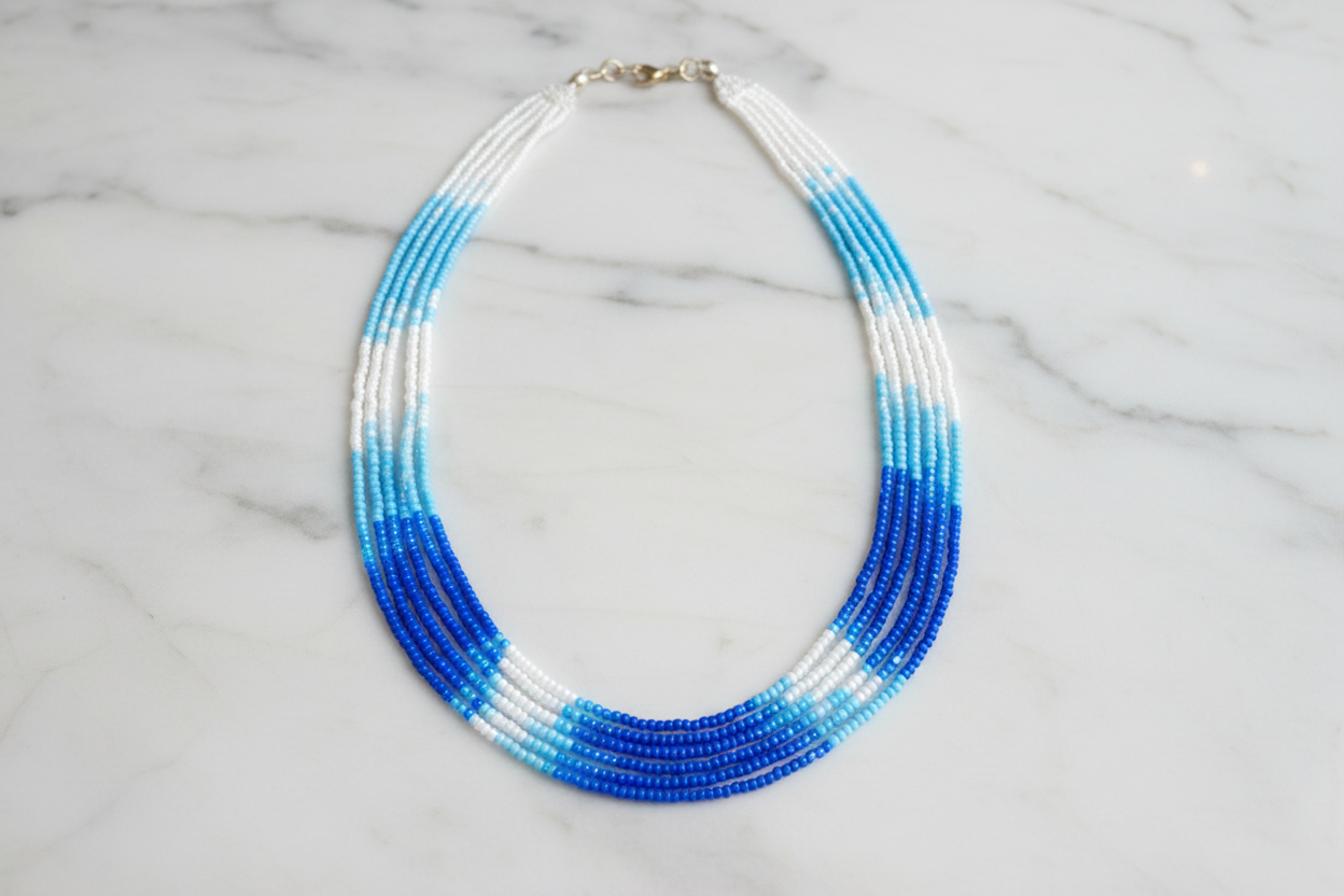 Flat lay of blue and white ombre seed bead necklace on white marble