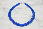 Flat lay of royal blue crystal bead necklace on white marble