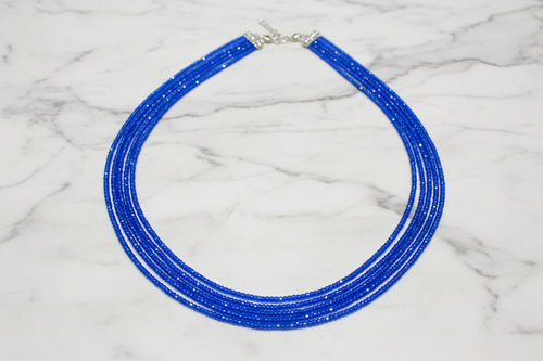 Flat lay of royal blue crystal bead necklace on white marble