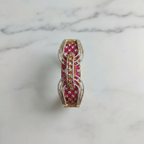 Flat lay top-down view of ruby pink open-work AD bangle with gold tone arch lattice design on white marble