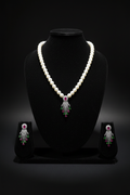 Pearl necklace with ruby and green AD tassel pendant set on dark velvet studio display