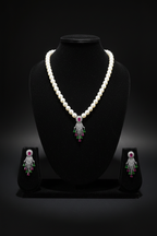 Pearl necklace with ruby and green AD tassel pendant set on dark velvet studio display