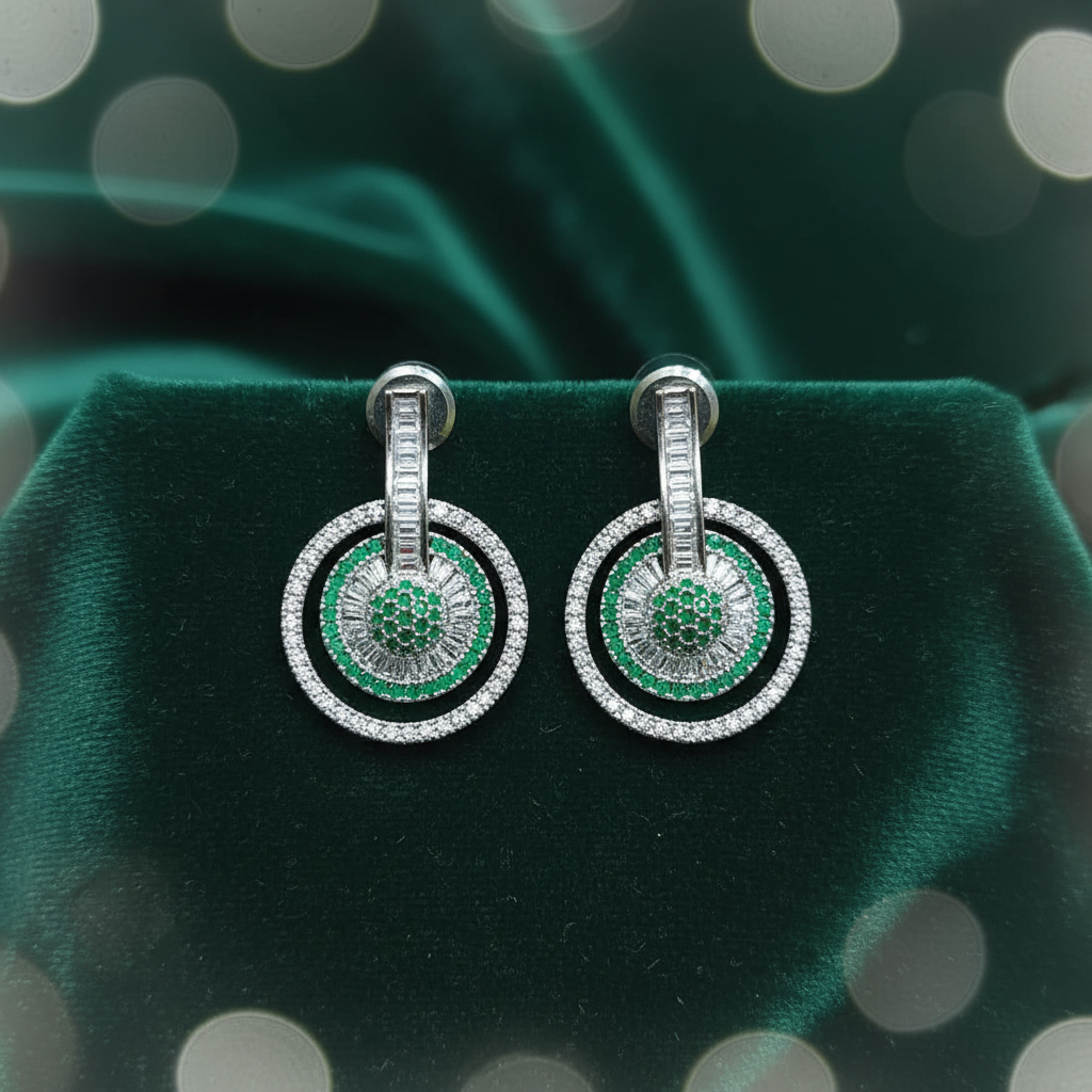 Emerald and diamond circle drop earrings on dark green velvet editorial flat lay