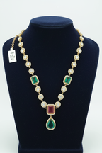 Polki-style gold AD necklace with emerald and ruby pendant drop on navy velvet display