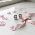 Blush pink CZ cushion rectangle halo stud earrings on white marble with cherry blossom petals - lifestyle style
