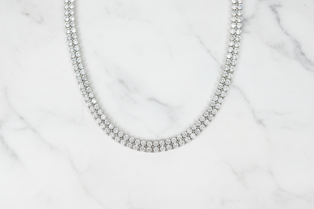 Flat lay of white AD double-row tennis necklace on white marble