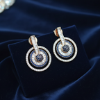 Sapphire blue circle drop earrings on navy velvet editorial flat lay