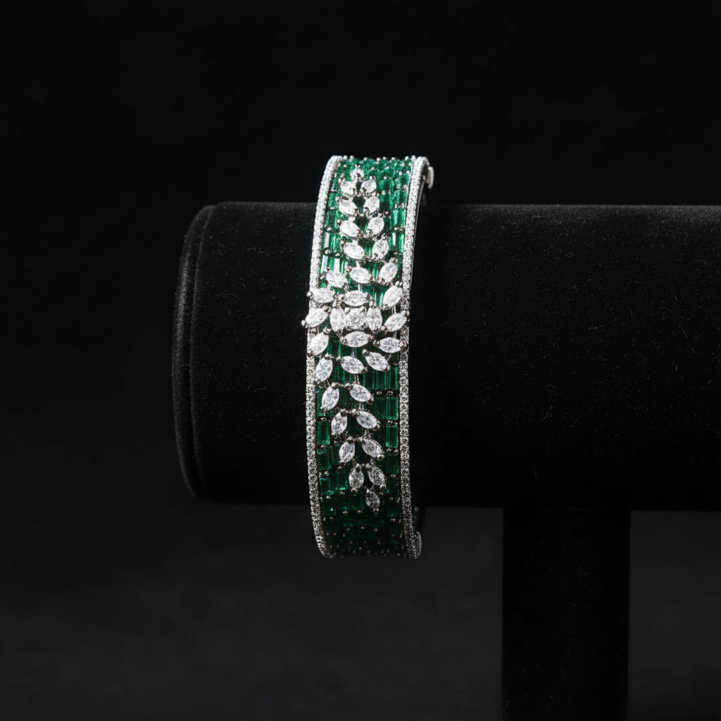 Emerald green baguette AD bangle with white marquise leaf overlay on dark velvet studio display