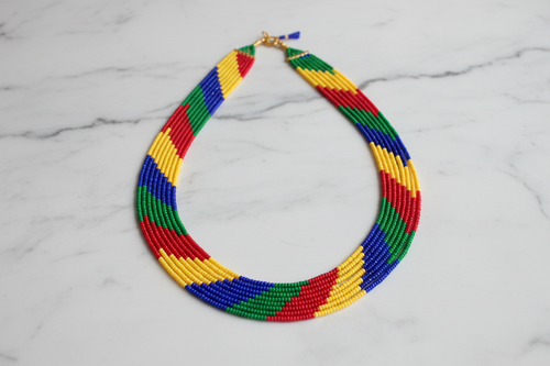 Flat lay of rainbow stripe seed bead necklace on white marble
