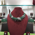 Emerald green and white AD pave twisted rope choker necklace set on burgundy velvet display