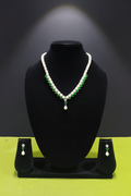 Pearl and emerald green AD necklace set with earrings on dark velvet studio display