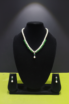 Pearl and emerald green AD necklace set with earrings on dark velvet studio display