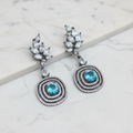 Blue topaz leaf cluster circular halo drop earrings editorial promotional image on marble