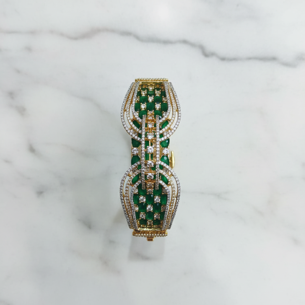 Flat lay top-down view of emerald green open-work AD bangle with gold tone arch lattice design on white marble