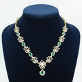 Emerald green and white AD botanical leaf necklace with pearl and emerald pendant on navy velvet display