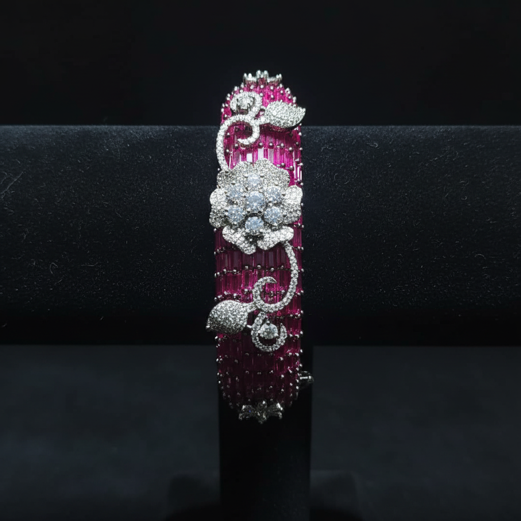 Ruby pink baguette AD bangle with white floral AD sculpture on dark velvet studio display