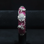 Ruby pink baguette AD bangle with white floral AD sculpture on dark velvet studio display