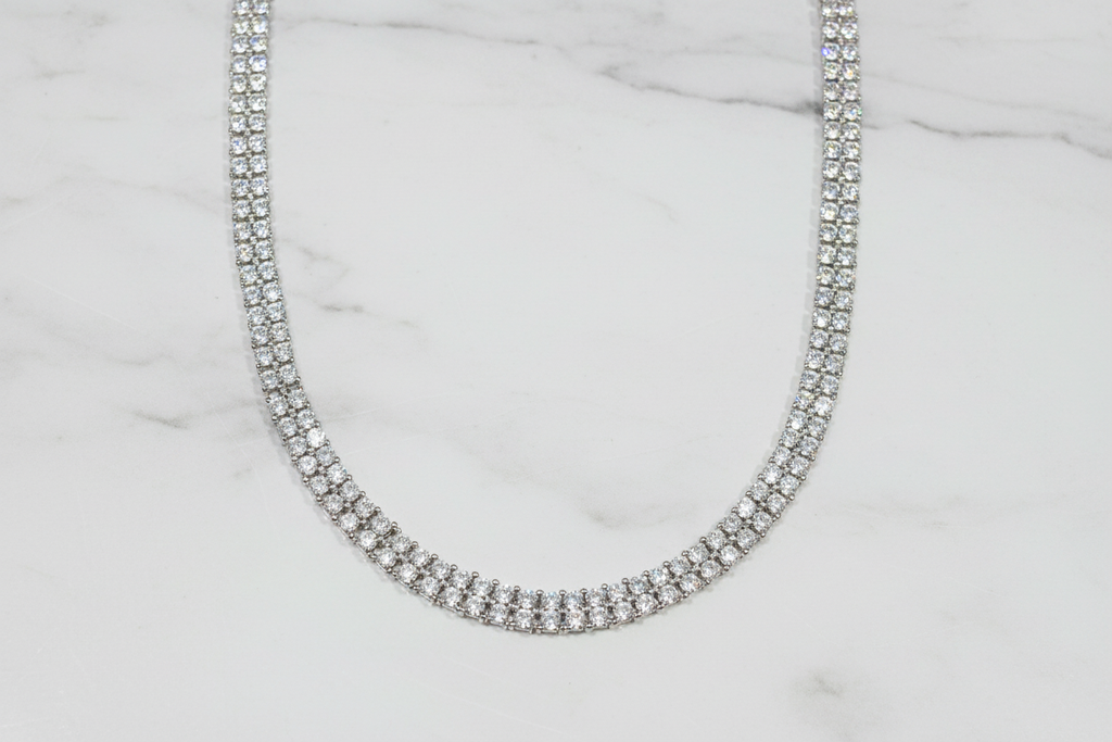 Flat lay of white AD diamond tennis necklace on white marble