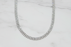 Flat lay of white AD diamond tennis necklace on white marble