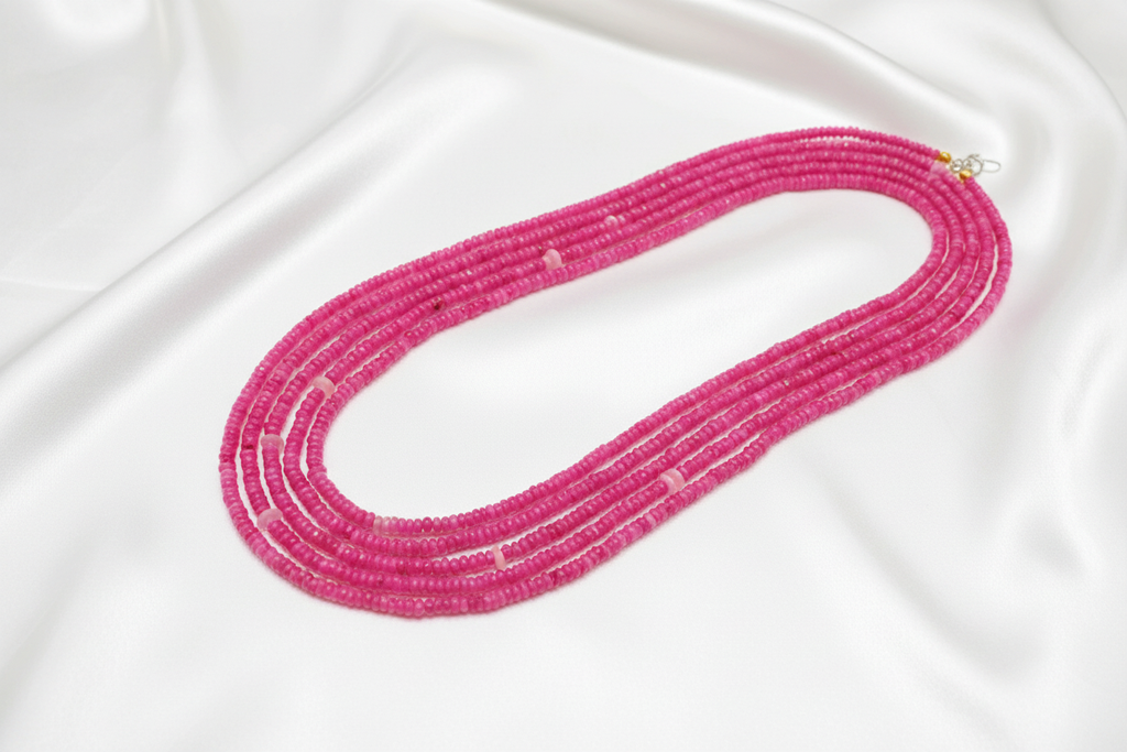 Flat lay of pink rondelle bead necklace on white silk