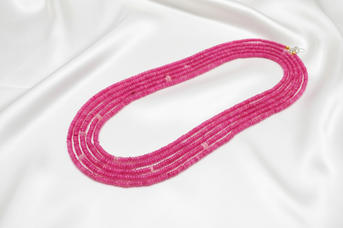 Flat lay of pink rondelle bead necklace on white silk
