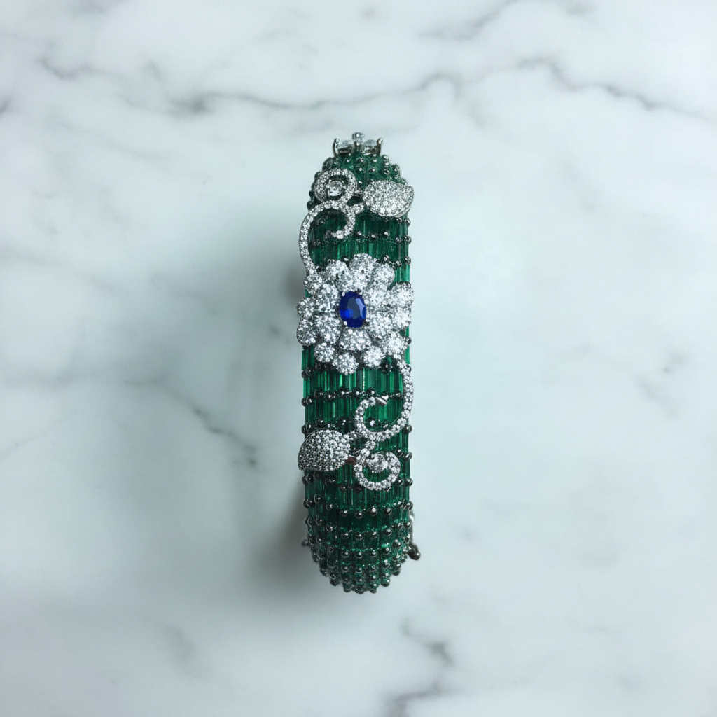 Flat lay top-down view of emerald green baguette AD bangle with white floral AD sculpture on white marble
