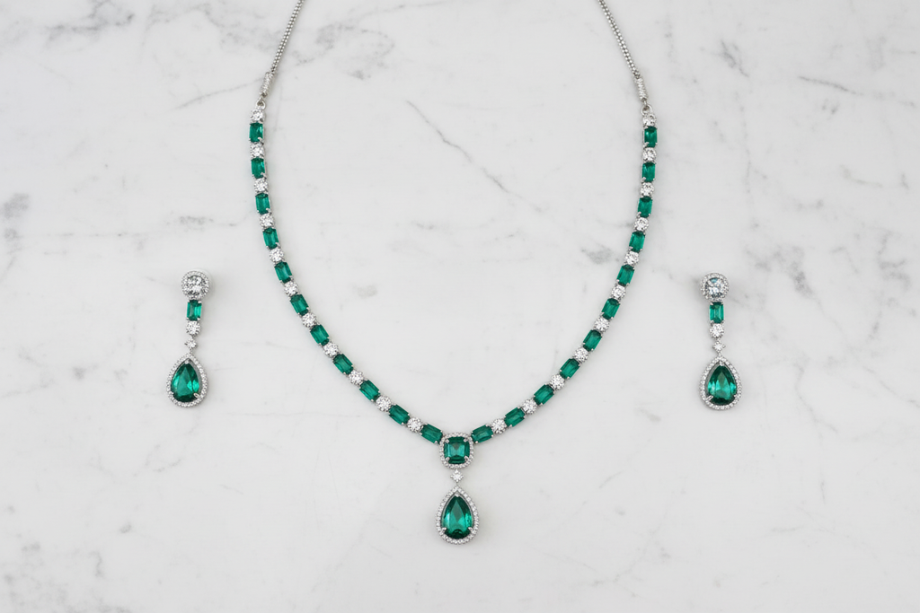 Emerald AD tennis necklace set flat lay on white marble
