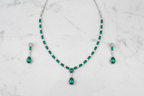 Emerald AD tennis necklace set flat lay on white marble