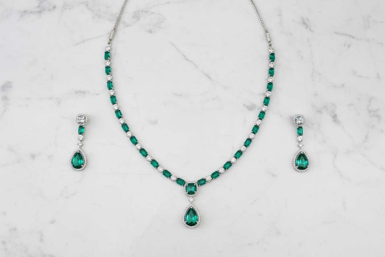 Emerald AD tennis necklace set flat lay on white marble