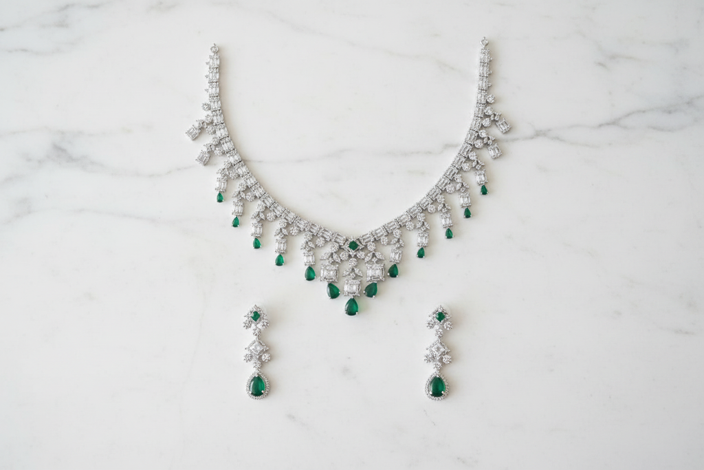 Emerald and diamond AD fringe necklace set flat lay on white marble