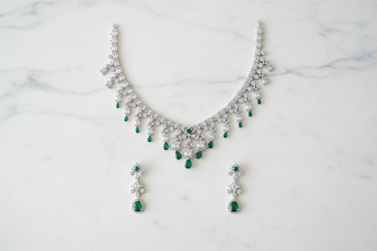 Emerald and diamond AD fringe necklace set flat lay on white marble