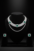 White AD tennis necklace with emerald stations and earrings on dark velvet studio display