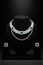 White AD tennis necklace with emerald stations and earrings on dark velvet studio display