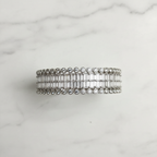 Flat lay top-down view of all-white baguette AD bangle with round polki AD border on white marble
